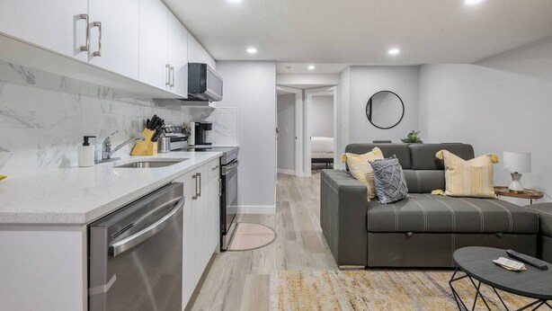 A modern kitchen with white cabinets, stainless steel appliances, and a marble backsplash. - Perfect 2BR Airdrie Suite - Near Calgary, WiFi (Airdrie)