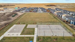 A residential area with houses, a sports court, and a large open field. - Perfect 2BR Airdrie Suite - Near Calgary, WiFi (Airdrie)