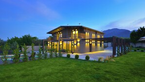 Une maison moderne dotée d’un vaste patio, d’une piscine et d’une pelouse bien entretenue.