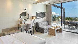 Une chambre d’hôtel moderne équipée d’un lit, d’un canapé, d’un bureau et d’un coin repas offrant une vue sur l’océan.