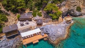 An aerial view of a coastal resort with wooden structures, a wooden deck, and clear turquoise waters. - Private Island-Style Ultra Luxury Villa Estate (Fethiye)