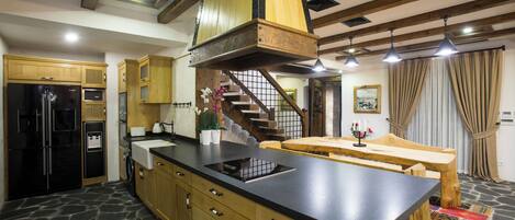 A kitchen with a stone floor, wooden cabinets, a black countertop, and a built-in stove.