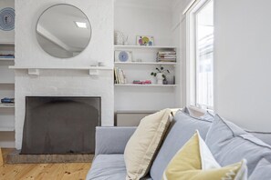 A living room with a fireplace, a grey sofa, and a white wall with shelves. - Tea-Tree Retreat, Rye (Rye)