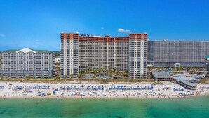 Un hotel frente a la playa con varios edificios altos, una playa de arena y un cielo azul despejado.