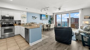 Una cocina moderna con una isla central, un comedor con vistas y un espacio de sala con balcón sobre el océano.