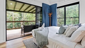 A bedroom with a large bed, a view of the outdoors, and a balcony. - Creekside Cottage pet friendly w pool (Perwillowen)