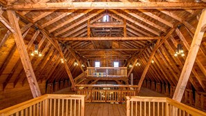 A spacious attic with wooden beams, a central staircase, and a balcony with railings. - Huge Farmhouse Estate on South Pond with Extreme Privacy: Host Weddings (Buckfield)