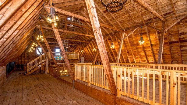 An attic room with wooden beams, a wooden staircase, and a chandelier. - Huge Farmhouse Estate on South Pond with Extreme Privacy: Host Weddings (Buckfield)