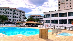 Un hotel con area piscina, diversi edifici e posti a sedere all'aperto.