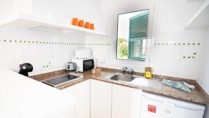 Une cuisine moderne avec des armoires blanches, des comptoirs en granit, un four à micro-ondes encastré, un grille-pain et un lave-vaisselle.