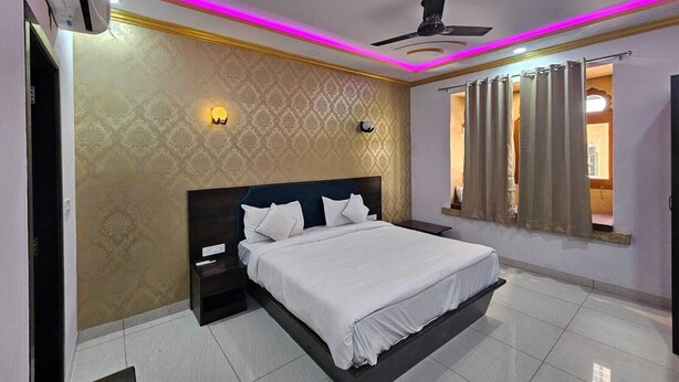 Una camera da letto con un letto, comodino, applique, ventilatore a soffitto e una finestra con tende.