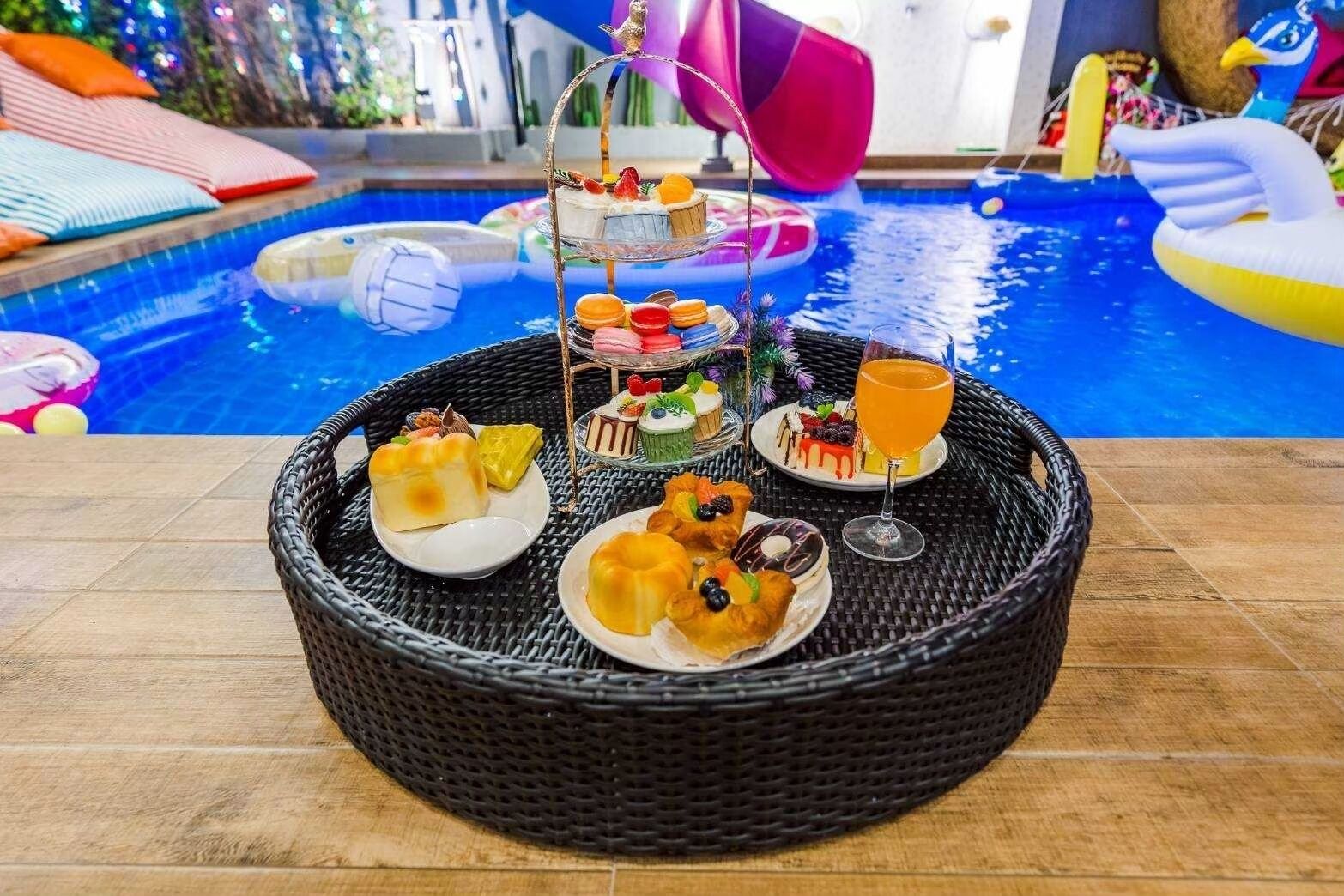 A poolside buffet with various desserts and a drink.