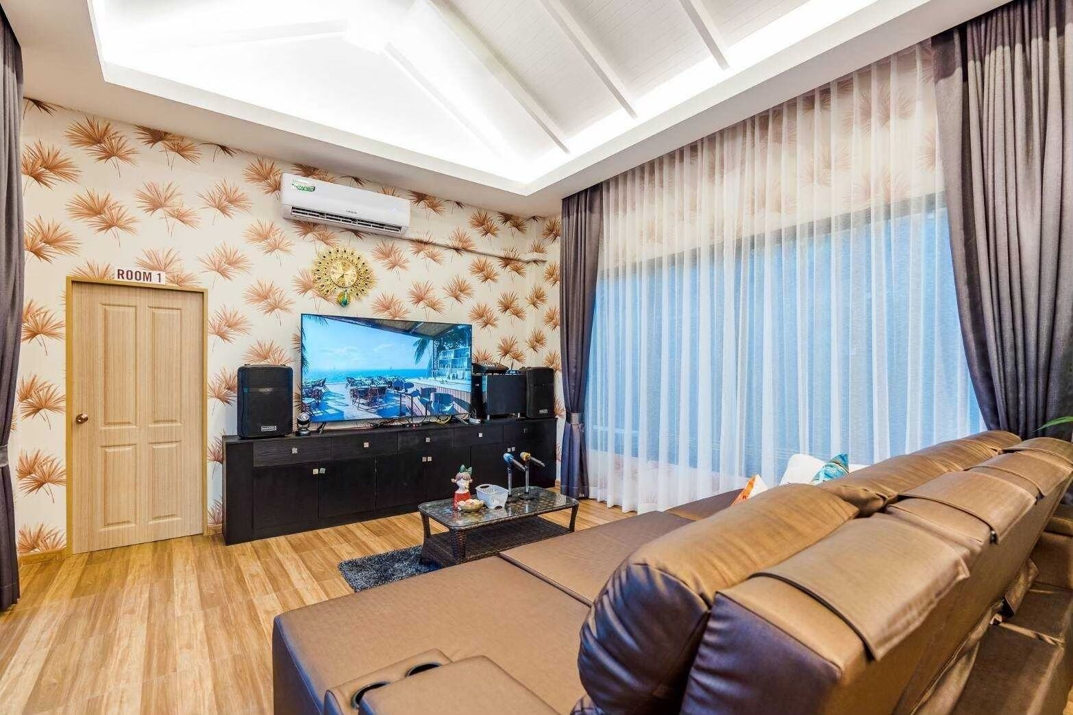 A living room with a sofa, a television, a coffee table, and a wall-mounted air conditioner.