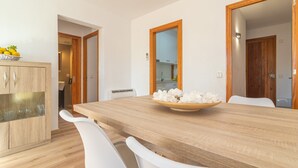 Een moderne eethoek met een houten tafel, witte stoelen en een kast van hout met glazen deuren.