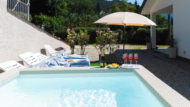 Una piscina con sillas de descanso y una mesa con bebidas y aperitivos.