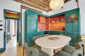 Una cucina moderna con mobili color petrolio, un tavolo da pranzo rotondo e un soffitto in legno.