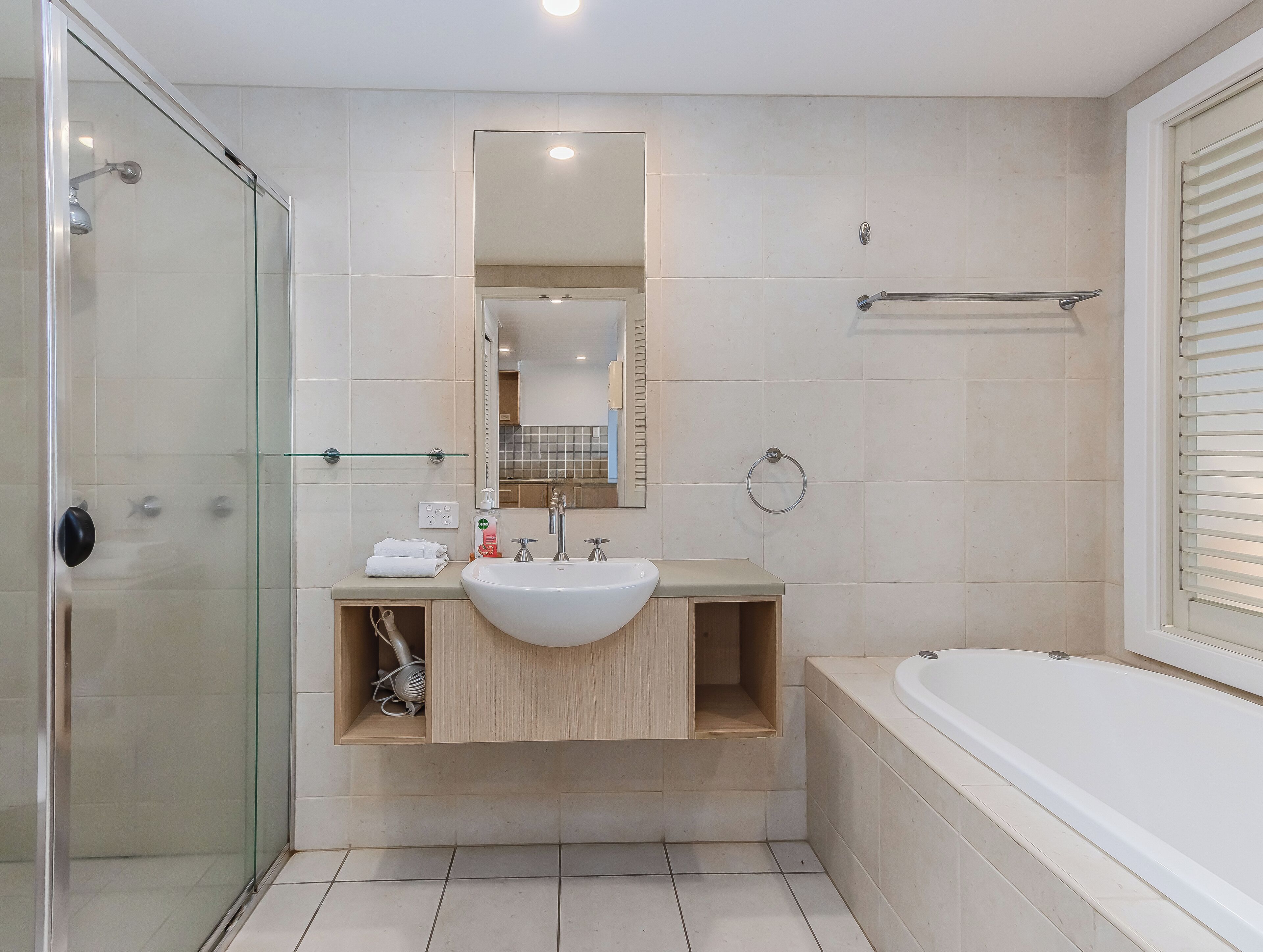 Ein modernes Badezimmer mit Duschkabine aus Glas, einem Waschbecken mit Spiegel darüber und einer Badewanne.