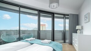 Une chambre d’hôtel moderne dotée d ’un grand lit, d’un balcon offrant une vue sur la ville et d’un bureau avec une lampe.