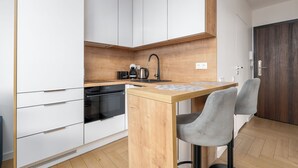 Une cuisine moderne avec des armoires blanches, un plan de travail en bois, un four encastré et une machine à café.
