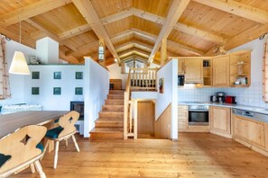 A spacious kitchen with wooden flooring, a dining area with a wooden table and chairs, and a staircase leading to an upper level. - Pinzgau Ski Chalet Retreat With Balcony (Wald im Pinzgau)