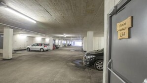 Un parking avec des piliers en béton, une voiture blanche et une voiture noire qui y sont garées.