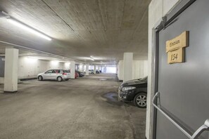A parking garage with concrete pillars, a white car, and a black car parked. - Pinzgau Ski Chalet Retreat With Balcony (Wald im Pinzgau)
