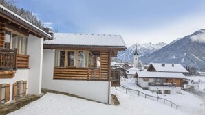 Un village de montagne enneigé, avec des bâtiments en bois et une église.