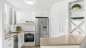 A modern kitchen with white cabinetry, stainless steel appliances, and a wooden countertop.