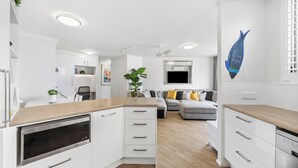 A modern kitchen with white cabinetry, a built-in oven, and a wooden countertop.