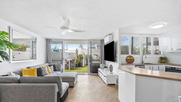 A modern apartment with a living room, kitchen, and balcony.