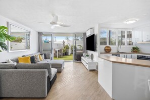 A modern apartment with a living room, kitchen, and balcony.