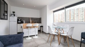 Eine moderne Küche mit Essbereich, einer Couch und Blick auf hohe Gebäude.