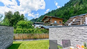 A stone wall, a wooden fence, and a table with breakfast items. - Stylish Neukirchen Home for 8 Guests (Neukirchen am Grossvenediger)
