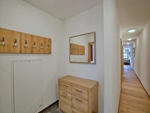 Ein Flur mit einem Holzkasten, einem Spiegel und einem Kleiderhaken.