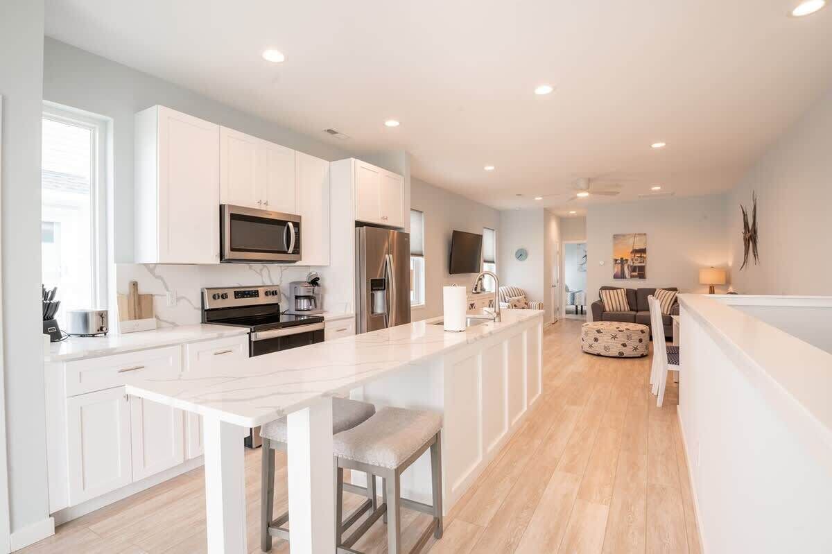 A modern kitchen with white cabinets, stainless steel appliances, and a long island with bar stools.