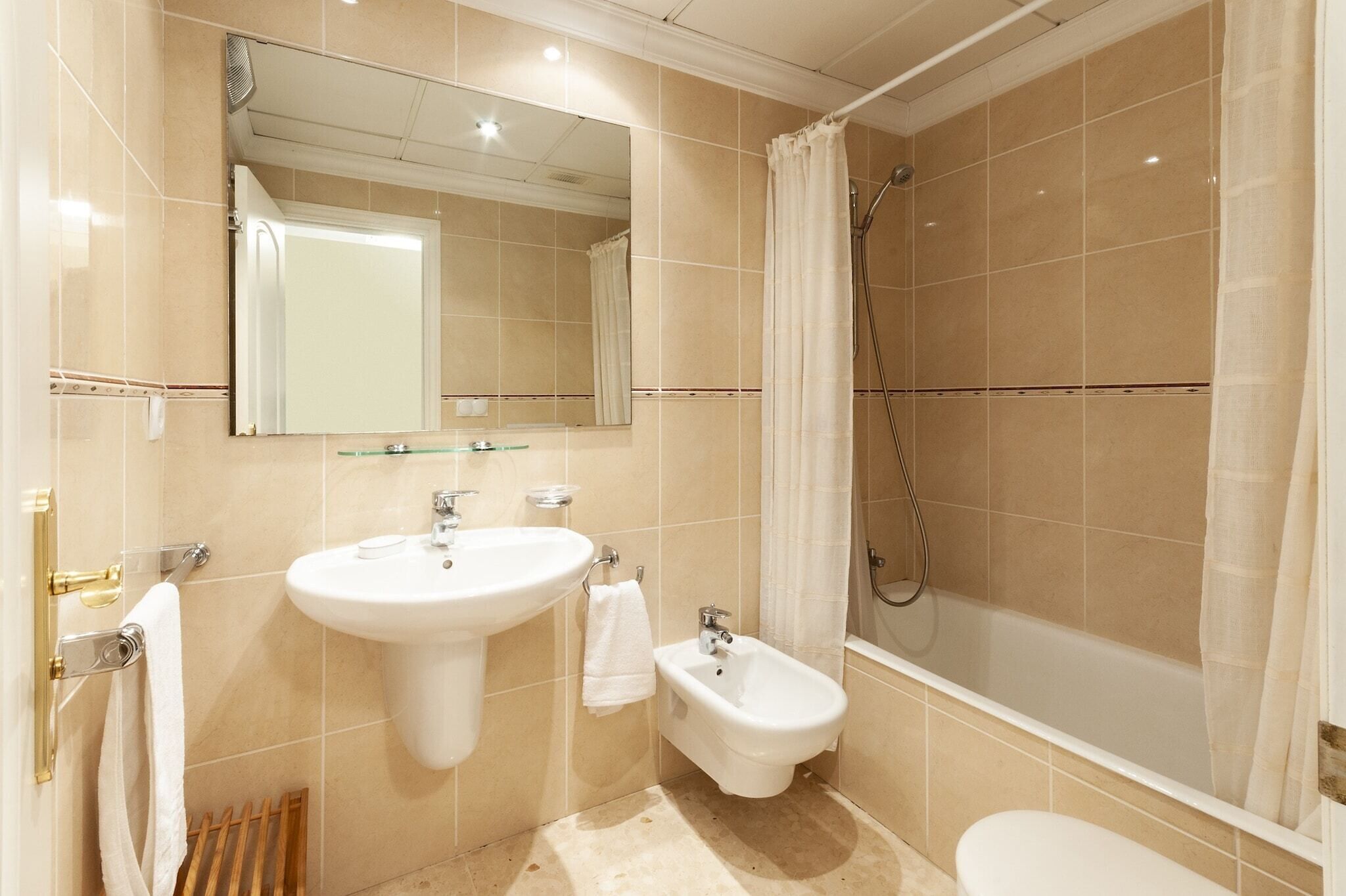 A modern bathroom with a sink, bidet, and shower.