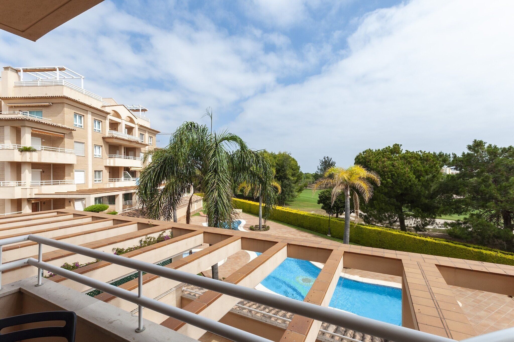 A residential building with a swimming pool, balconies, and a landscaped garden.