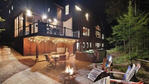 Un edificio de varios niveles con asientos al aire libre, una chimenea y equipo de esquí.