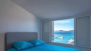 Un dormitorio con cama, vistas al mar y un muelle para barcos.