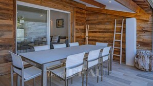 Un comedor con una mesa larga y sillas, paredes de madera y una escalera.