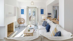 Un salon moderne avec un canapé, une table basse en bois, un fauteuil en osier et une vue sur l’extérieur grâce à une porte vitrée.