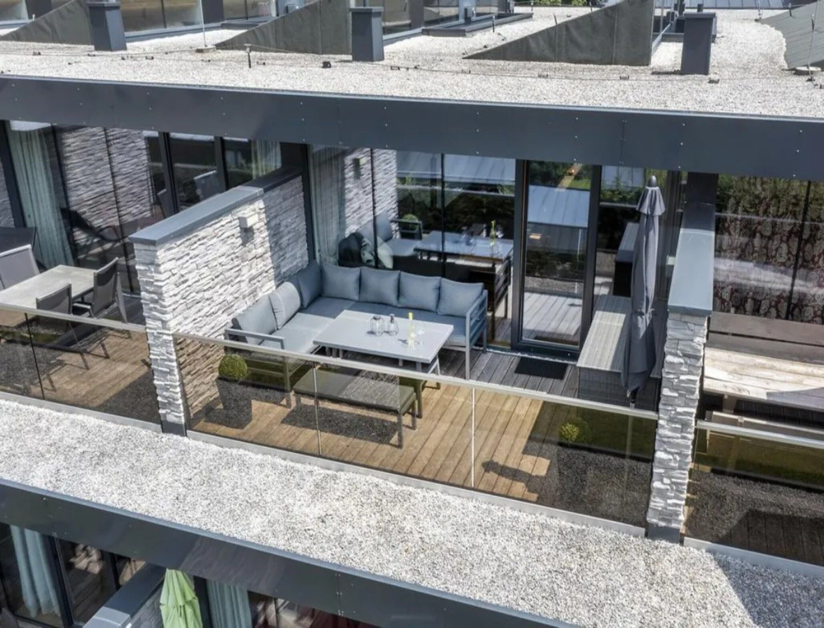 A modern outdoor living area with a stone wall, a seating area, and a dining table.