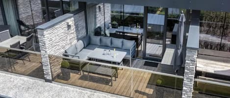 A modern outdoor living area with a stone wall, a seating area, and a dining table.