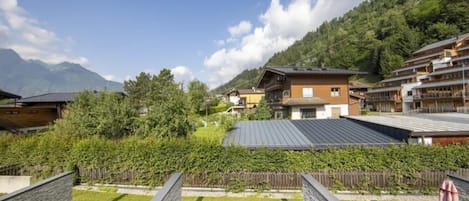 A hotel with a view of mountains, a wooden fence, and a grassy lawn.