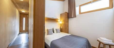 Une chambre à coucher avec un lit, une table de chevet, une fenêtre et un plafond en bois.