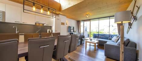 A modern kitchen with wooden cabinets and a dining area with chairs and a table.