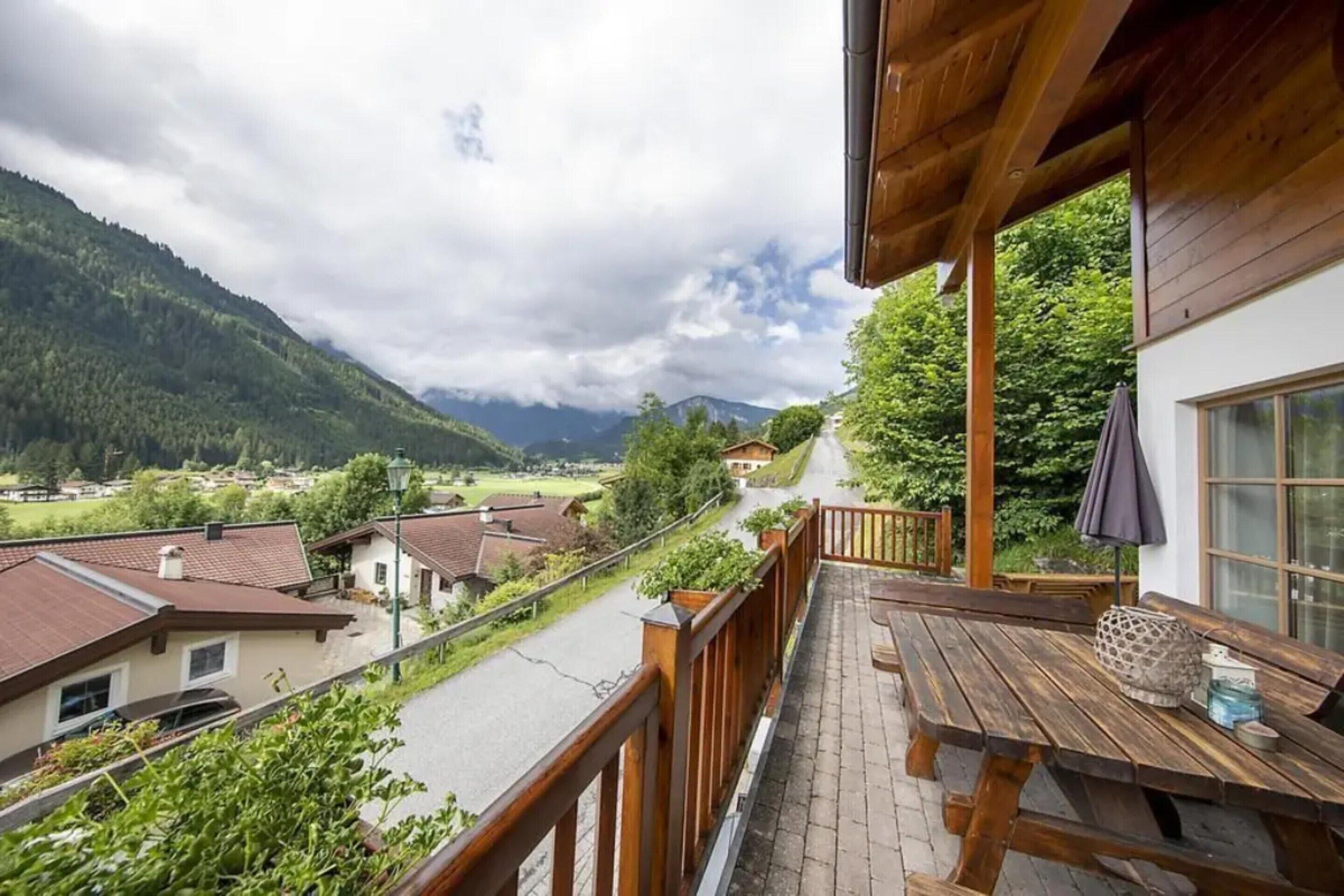 Un balcon avec une table en bois et une vue sur un paysage montagneux.