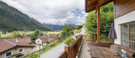 Un balcon avec une table en bois et une vue sur un paysage montagneux.