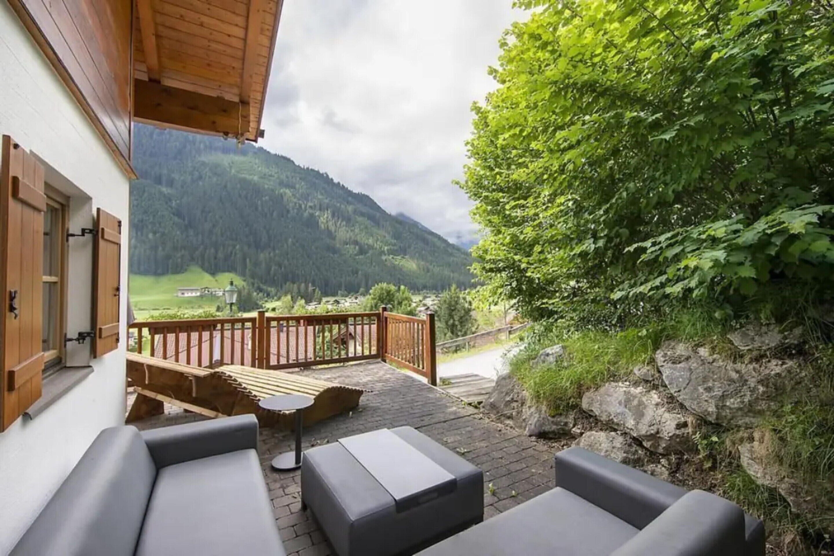A patio with outdoor furniture, a wooden deck, and a view of a mountainous landscape.