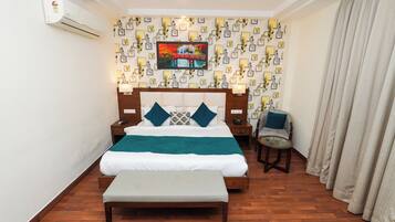A hotel room with a bed, bedside tables, a bench, a chair, and a wall-mounted air conditioner.